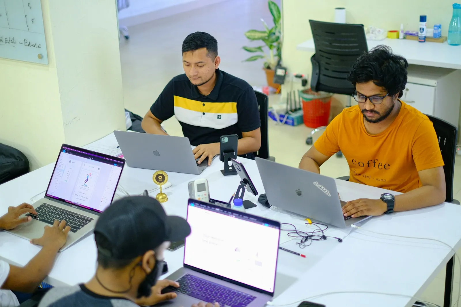 Tim muda bekerja bersama di meja penuh laptop