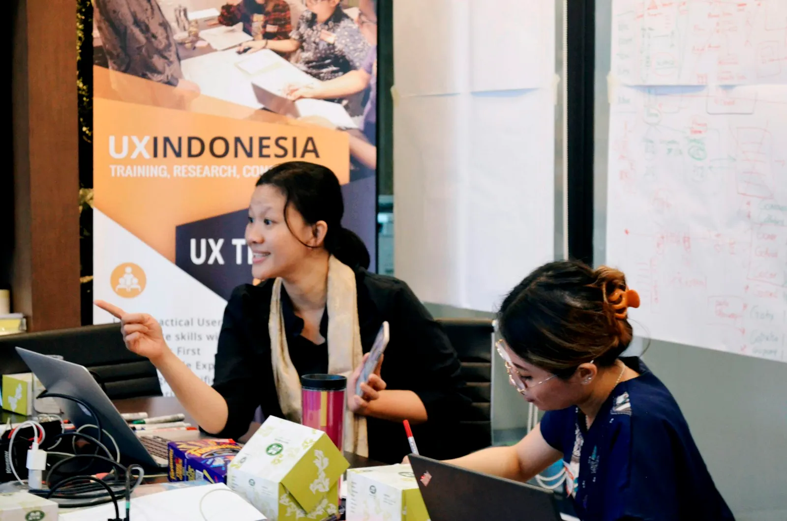 Dua perempuan menyusun strategi di meja kerja